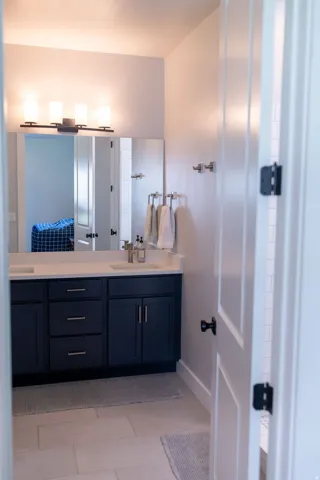 Dual-sink vanity with dark cabinetry, integrated sinks, and polished countertops