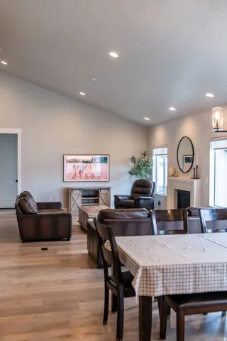Vaulted ceiling with recessed lighting, wood-finish flooring, and a built-in fireplace with a mantel