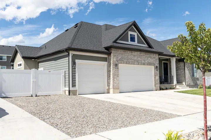 Exterior featuring gray brick and horizontal siding, a dark shingle roof, two garage doors, and a covered entry with white pillars