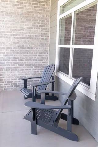 Exterior featuring light brick siding, horizontal panel siding, a large multi-pane window, and a concrete patio