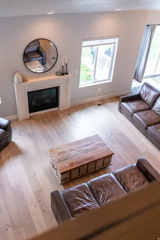 Light wood-finish flooring, recessed lighting, and a white fireplace with a dark insert