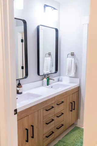 Dual vanity with integrated sinks, white countertop, and wood-finish cabinetry
