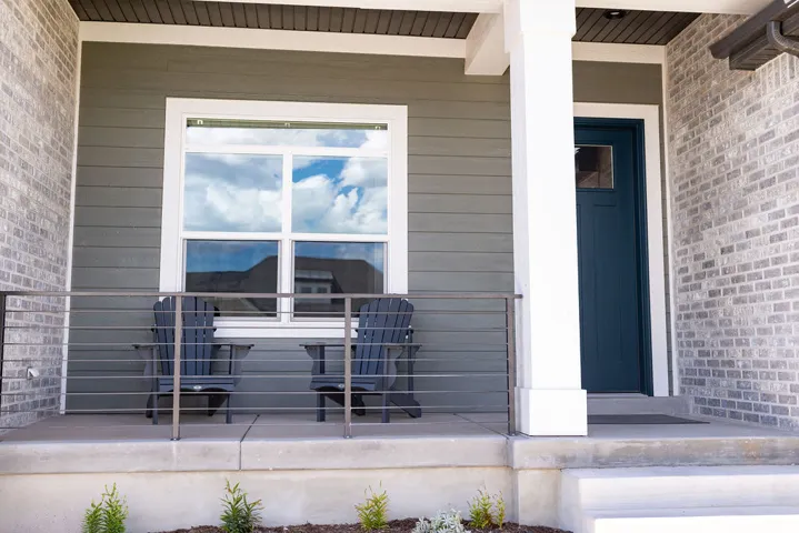 Front porch featuring brick and siding exterior, a prominent entry door, white window trim, and a horizontal cable railing