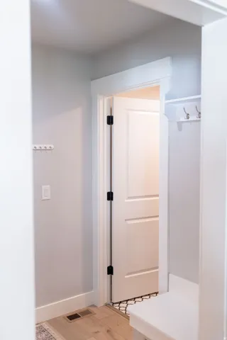 Built-in storage bench with coat hooks, light wood-finish flooring, and a paneled door with dark hardware