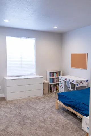Recessed ceiling lighting, light gray wall paint, window with horizontal blinds, and neutral-toned carpet flooring
