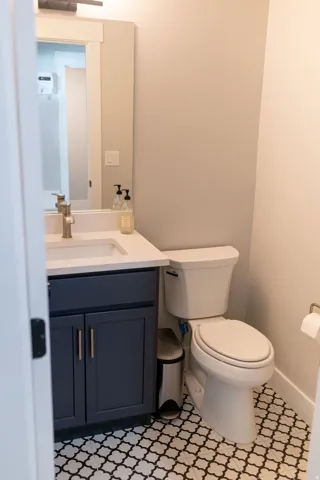 Powder room featuring a single vanity with dark blue cabinetry, a white countertop, an undermount sink, and patterned floor tile