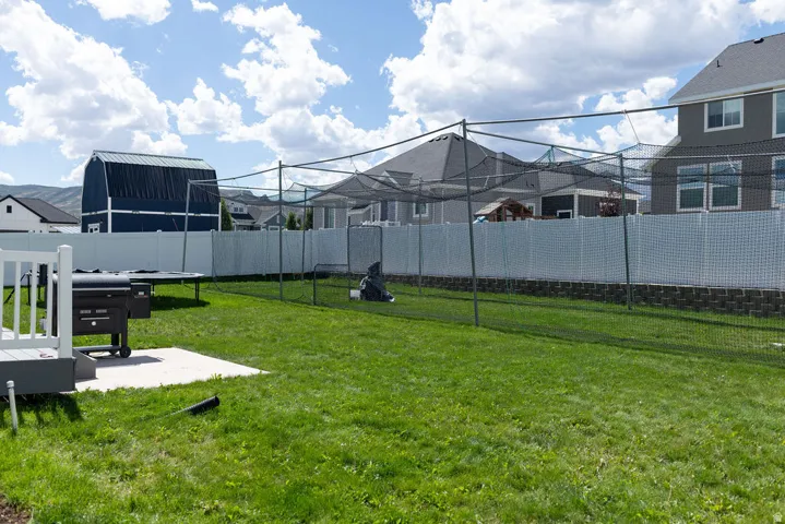 Expansive backyard featuring a lush lawn, privacy fencing, and a concrete patio