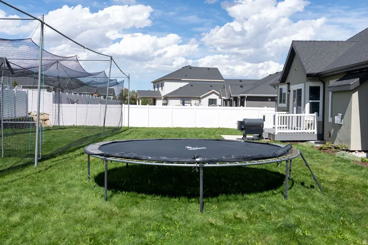 Expansive green lawn, white privacy fencing, and an exterior deck with white railings