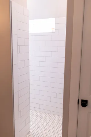 Walk-in shower with white subway tile walls and patterned floor tile