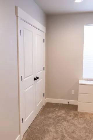 Recessed ceiling lighting, carpet flooring, white trim, white paneled doors with dark hardware, and a white window blind