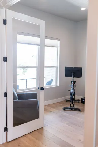 Room with wood-finish flooring, two windows with roller shades, and a recessed ceiling light