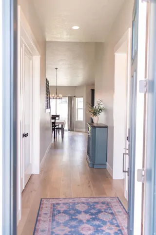 Hardwood-finish flooring, recessed lighting, and a chandelier illuminate the corridor