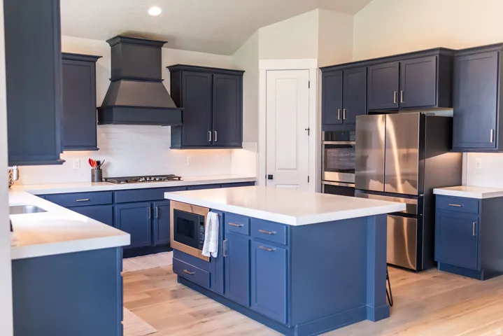 Kitchen featuring dark blue cabinetry, light countertops, stainless steel appliances, a center island, and wood-finish flooring