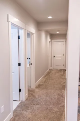 Hallway with neutral tone carpeting and recessed lighting