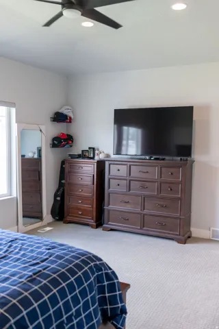 Recessed lighting, ceiling fan with integrated light, light-colored carpeting, window with natural light