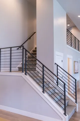 Staircase featuring contemporary black metal horizontal railings and carpeting