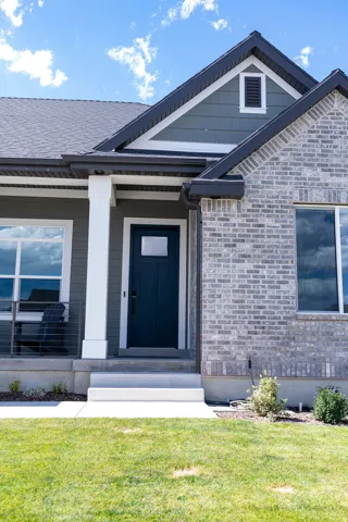 Exterior facade featuring brick and siding finishes, a dark entry door, and a covered porch