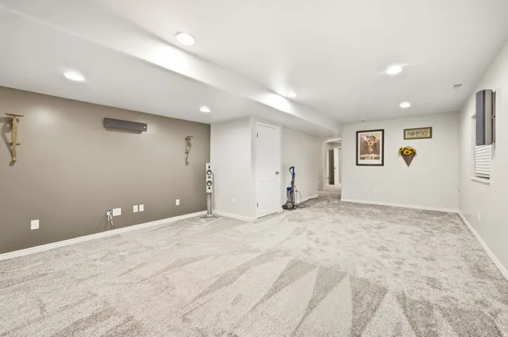 Recessed ceiling lighting, light gray wall paint, light gray patterned carpeting, white trim, and a white interior door