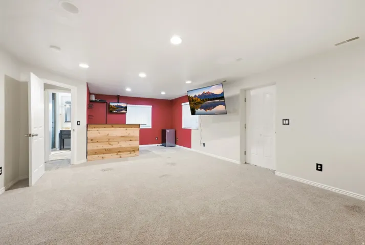Recessed lighting, light-toned carpeting, wood-finish bar, and a window