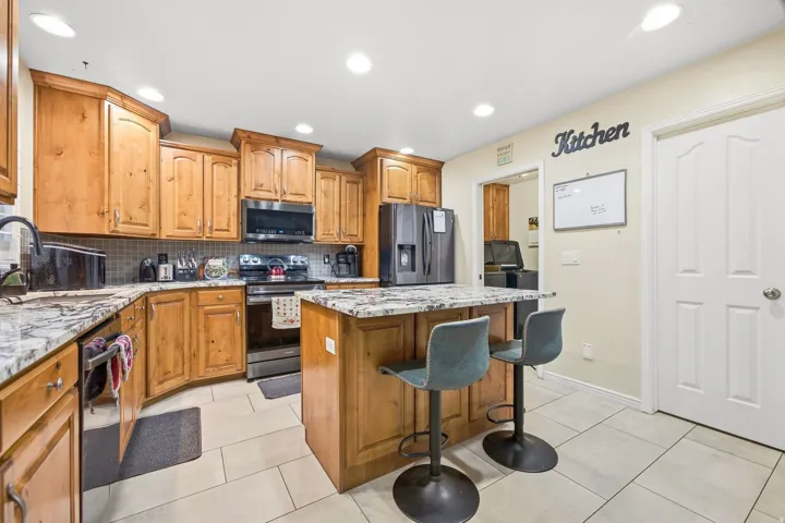 Kitchen featuring wood cabinetry, stainless steel appliances, a center island with countertop seating, and recessed lighting