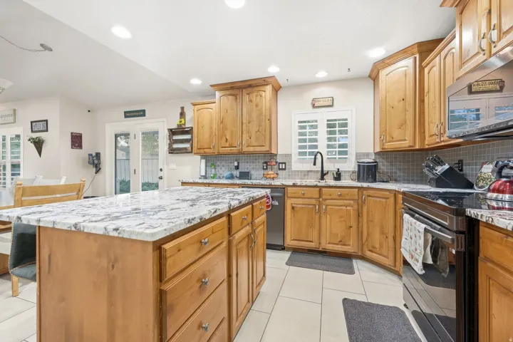 Kitchen featuring wood cabinetry, light-toned countertops, a tile backsplash, and stainless steel appliances