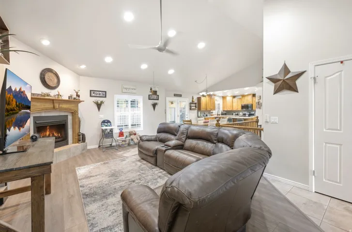 Vaulted ceiling, recessed lighting, ceiling fan, wood-finish flooring, and a fireplace with a detailed mantel