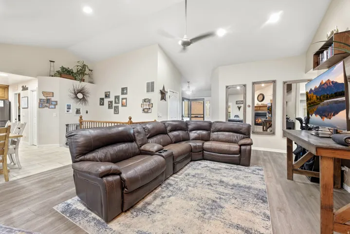Vaulted ceiling with a flush-mount ceiling fan, wood-finish flooring, and recessed lighting