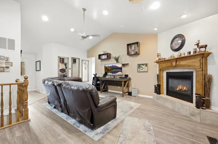 Wood-finish flooring, vaulted ceiling, recessed lighting, ceiling fan, and built-in fireplace with a wood mantle