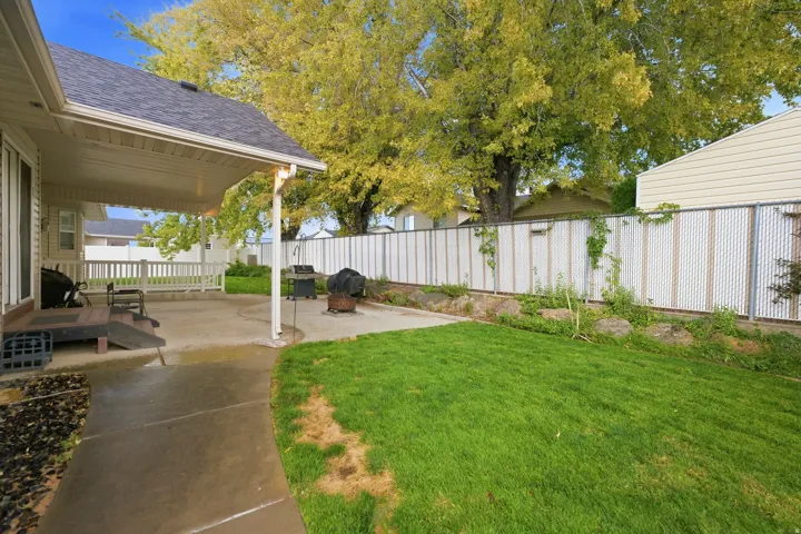 Expansive backyard featuring a concrete patio, covered porch area, and a privacy fence