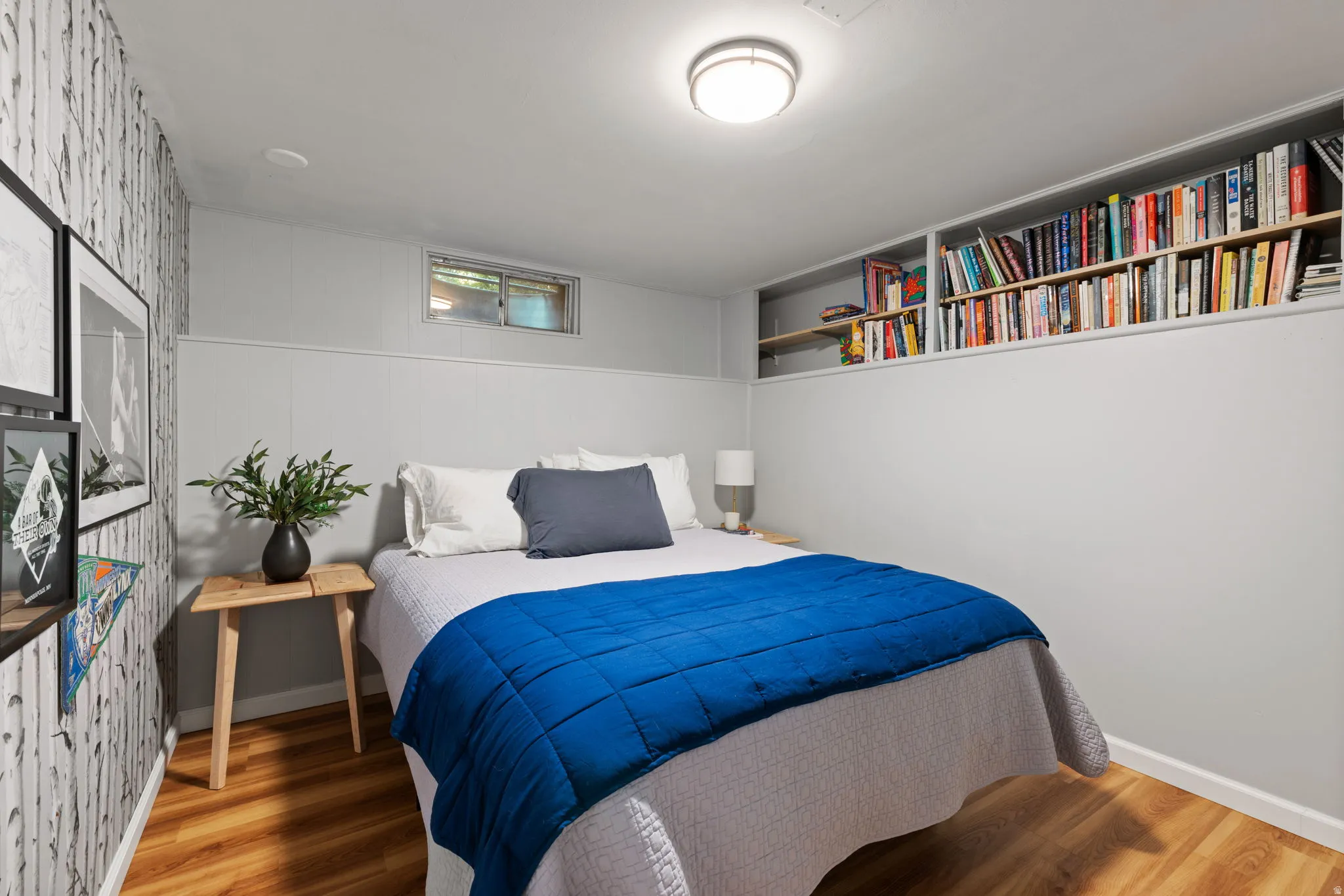 Wood-finish flooring, built-in shelving, high wainscoting, and a flush-mount ceiling light