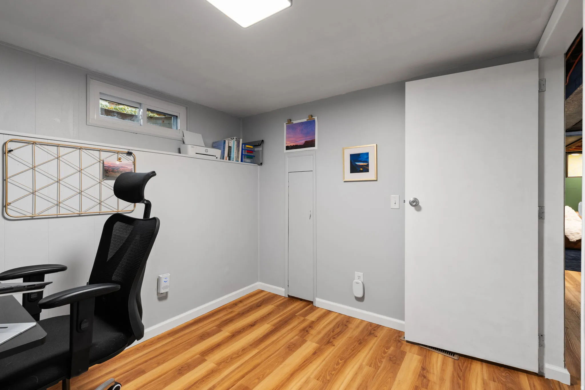 Wood-finish flooring, light gray wall paneling, and a single window