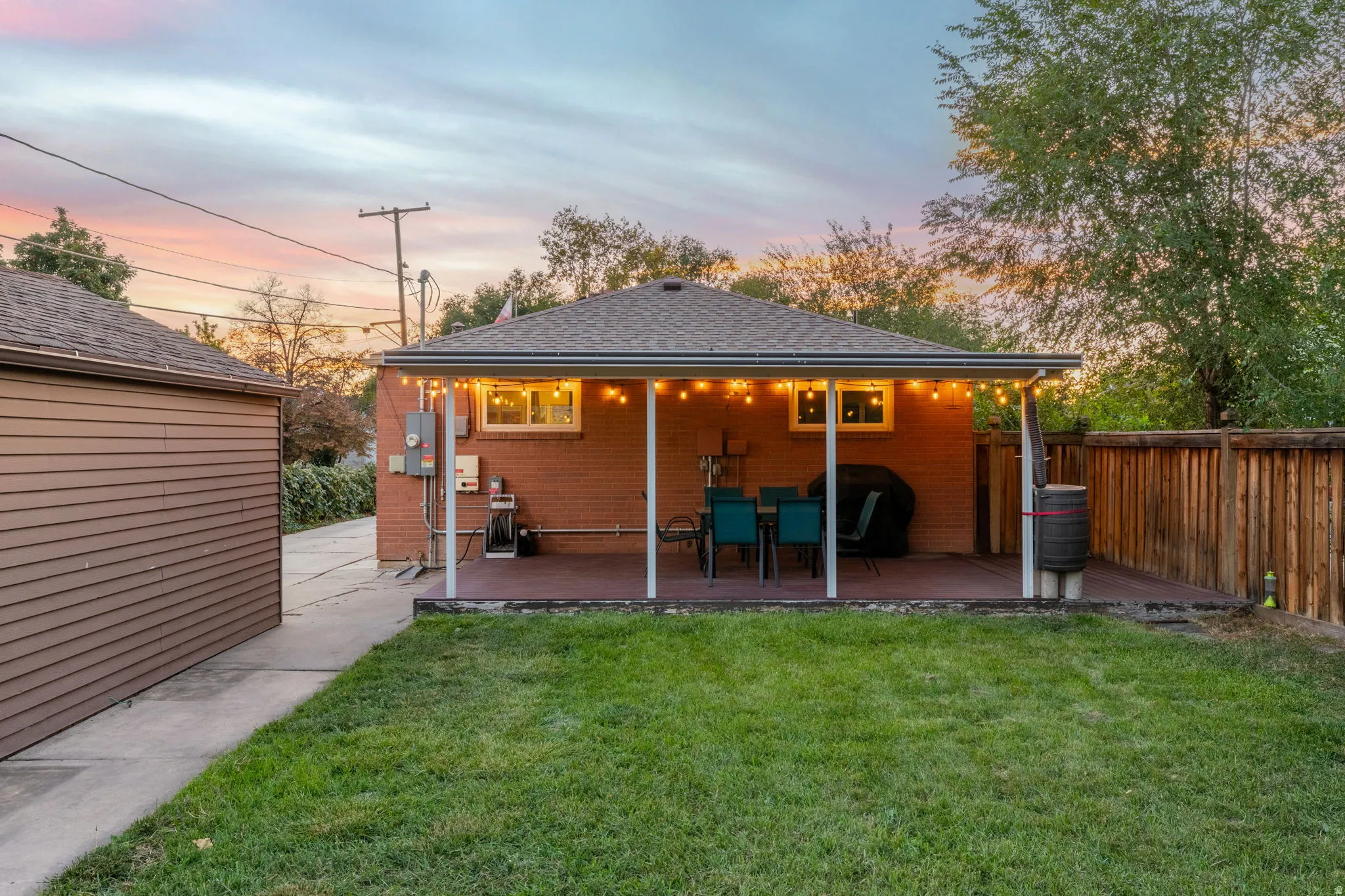 Expansive backyard featuring a covered patio, brick exterior, wood fence, and a detached garage with horizontal siding