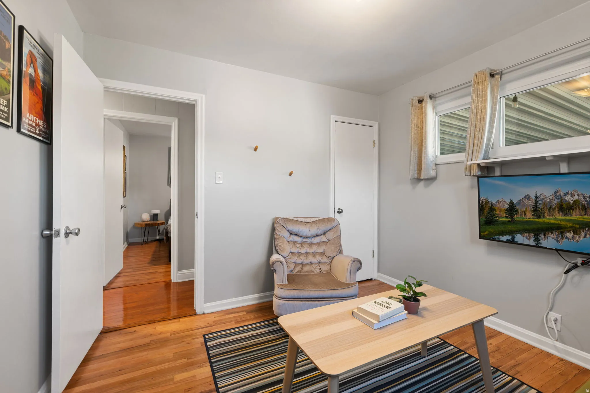 Hardwood-finish flooring, light gray wall paint, multiple doorways, and a wall-mounted display