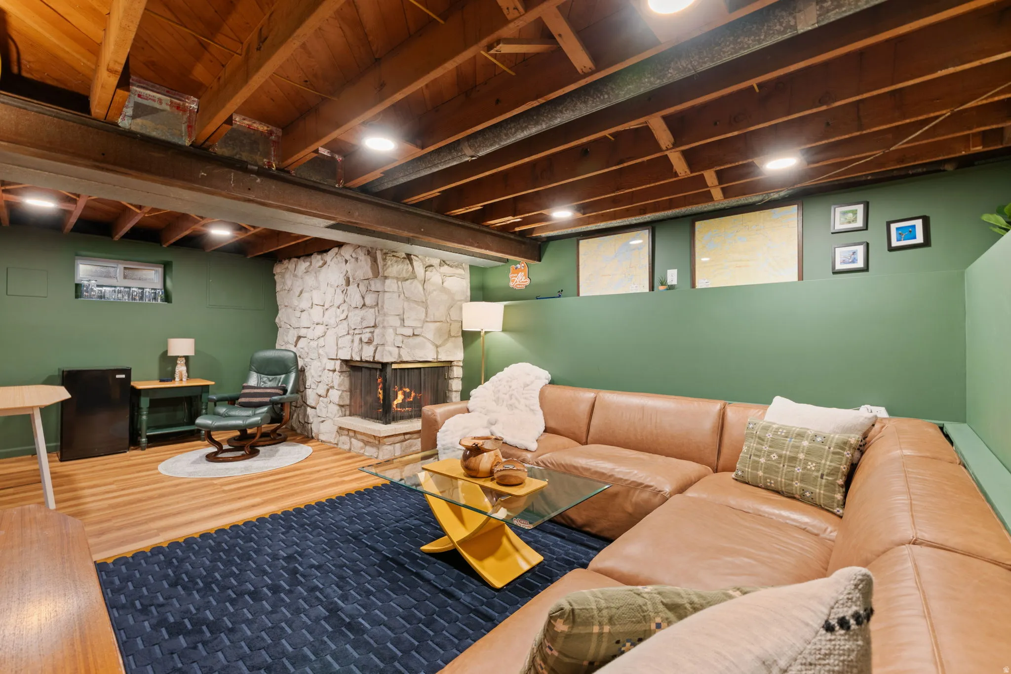 Exposed wood-beam ceiling, stone-clad fireplace with hearth, recessed lighting, wood-finish flooring, and multiple windows