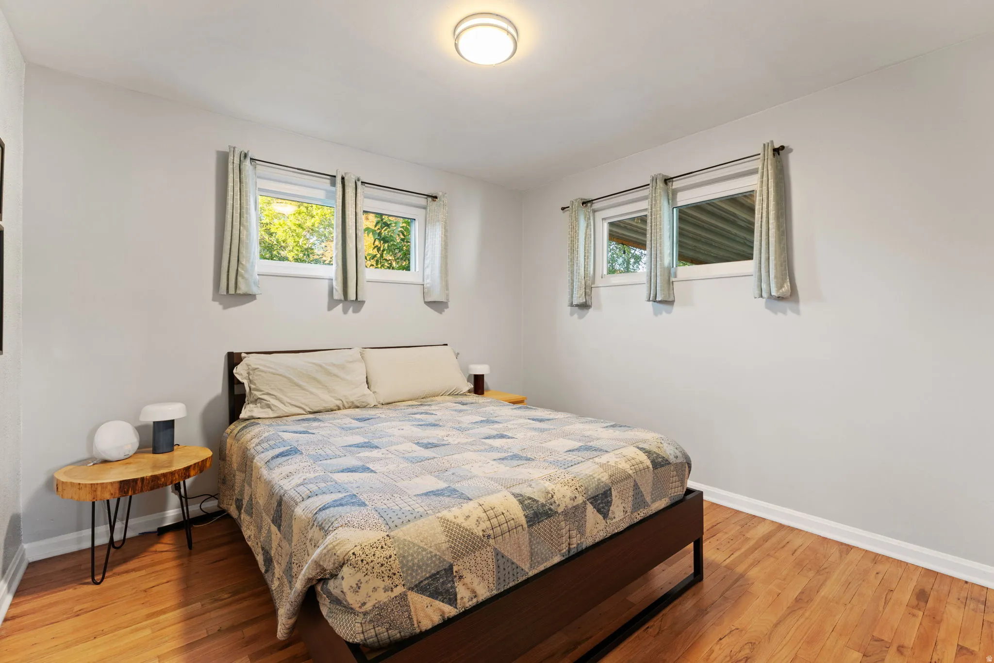 Hardwood flooring, painted walls, two windows, and a flush mount ceiling light