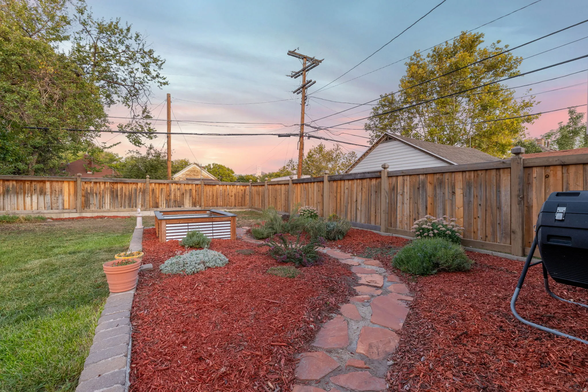 Landscaped yard featuring a stone pathway, mature plantings, and a raised garden bed