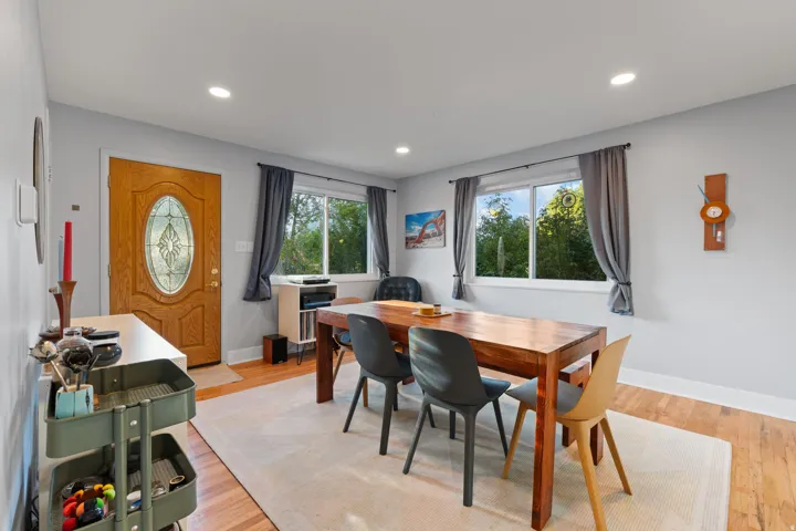 Wood-finish flooring, recessed lighting, and a leaded glass entry door