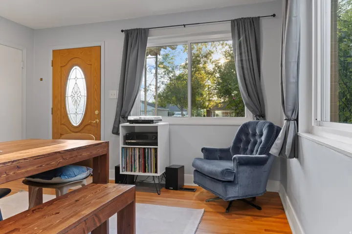 Wood-finish flooring, light gray wall paint, and a front entry door with an oval decorative glass insert