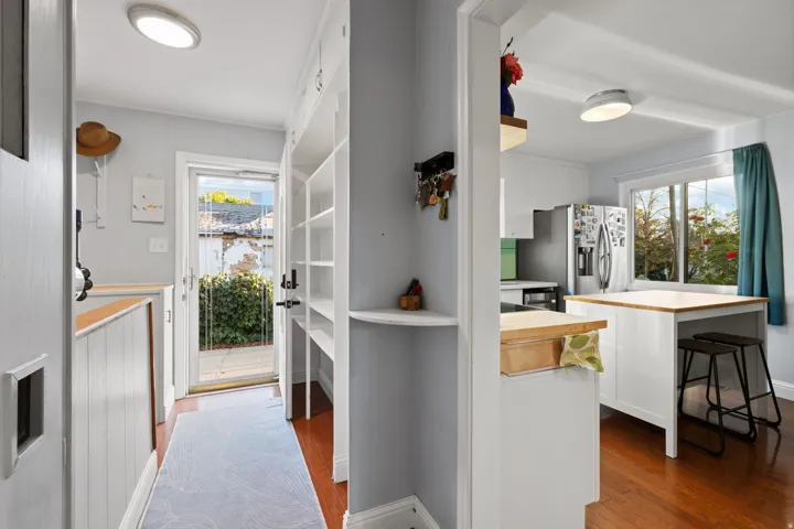 Hardwood flooring, built-in shelving, white cabinetry, and a full-light exterior door