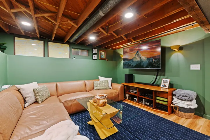 Exposed wood beam ceiling with recessed lighting, green accent walls, wood-finish flooring, and built-in wall sconces