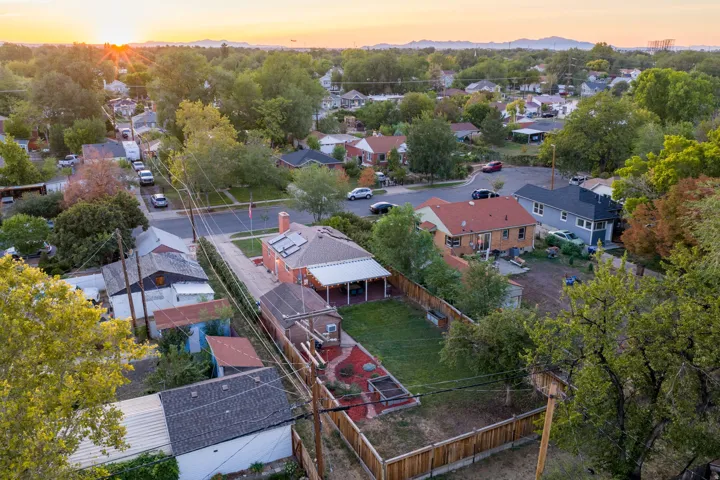Expansive lot featuring a main residence with a covered patio, a detached structure, manicured lawn, and mature trees