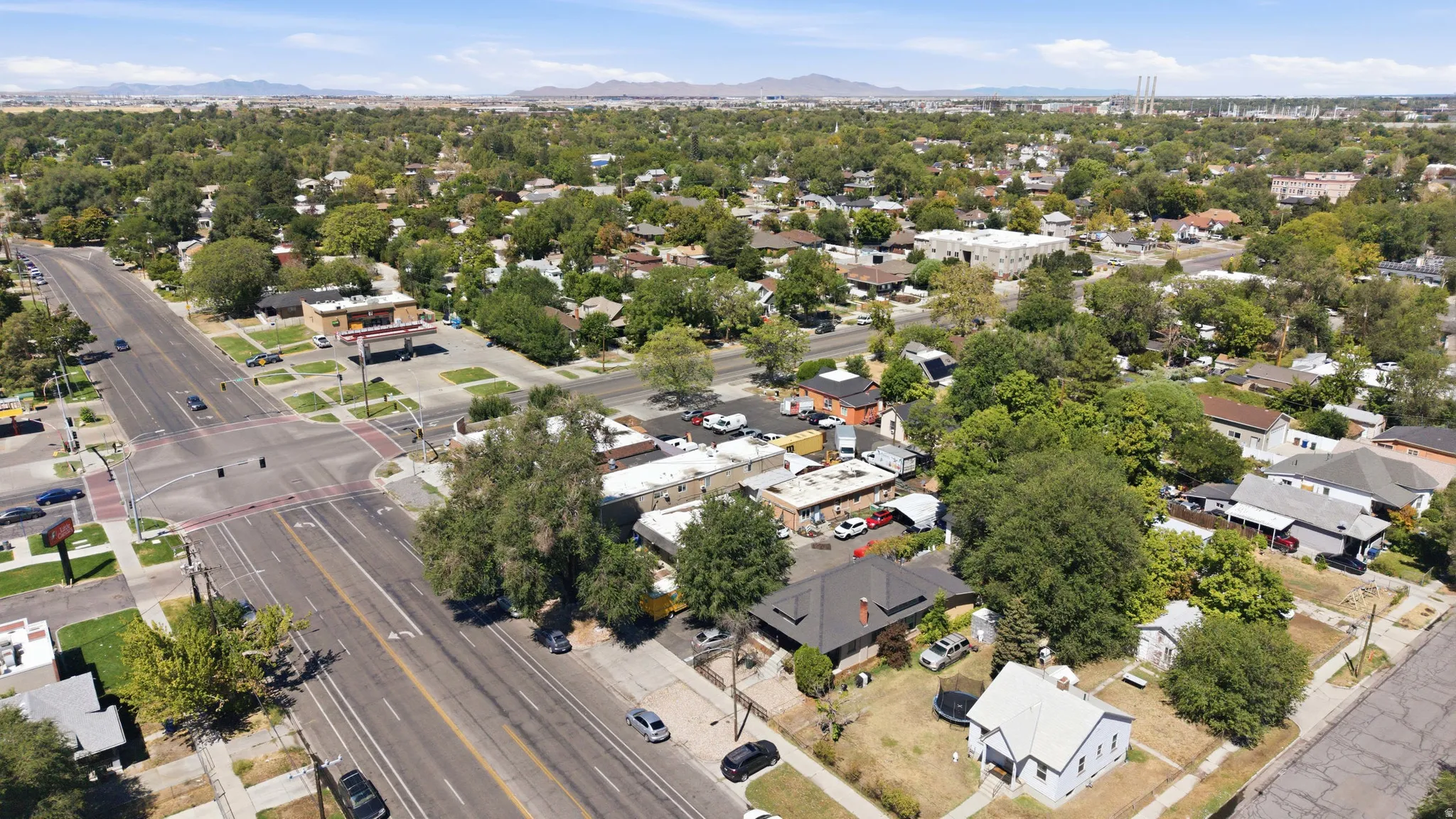 Aerial perspective showcasing a tree-lined residential area with a prominent intersection and commercial establishments