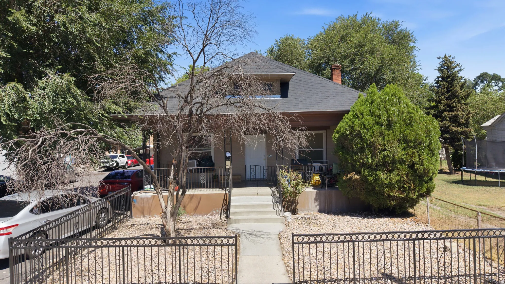 Front porch with metal railing, concrete stairs, and a gravel front yard