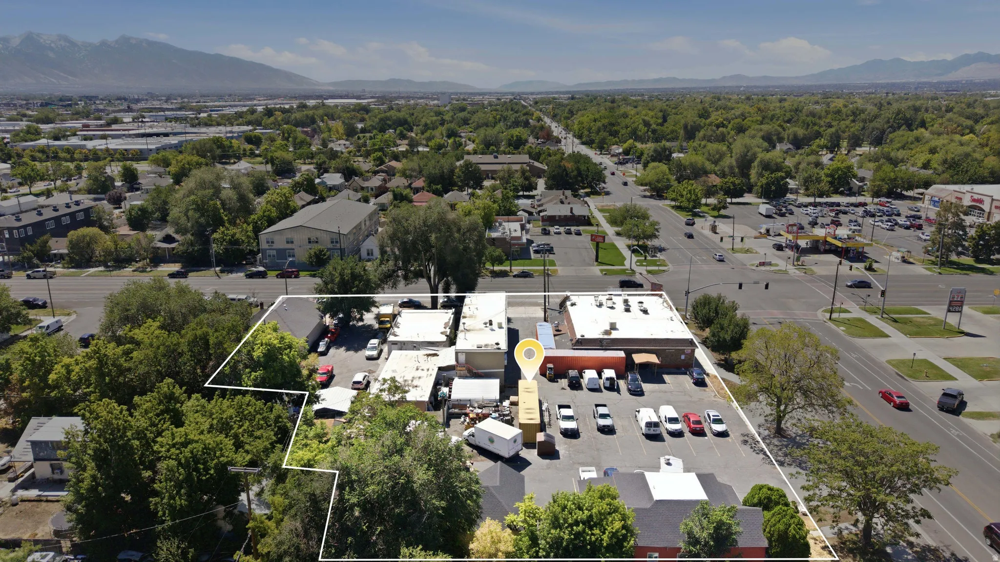 Aerial perspective showcasing commercial buildings, expansive surface parking, and mature trees within the property boundary