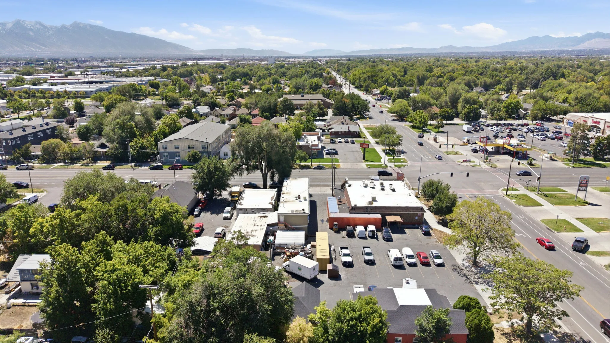 Aerial perspective showcasing a commercial property with an adjacent parking lot, surrounded by mature trees
