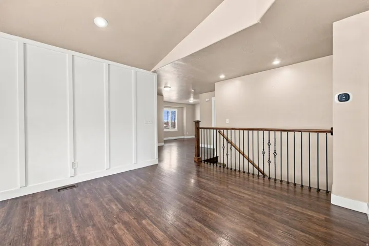 Wood-finish flooring throughout, board and batten accent wall, recessed lighting, and a staircase with wrought iron balusters and a wood handrail