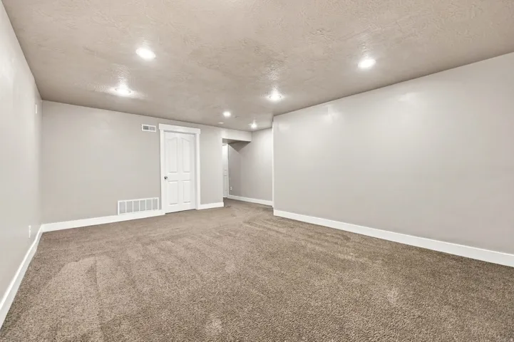 Neutral wall paint, recessed lighting, white trim, and a paneled door