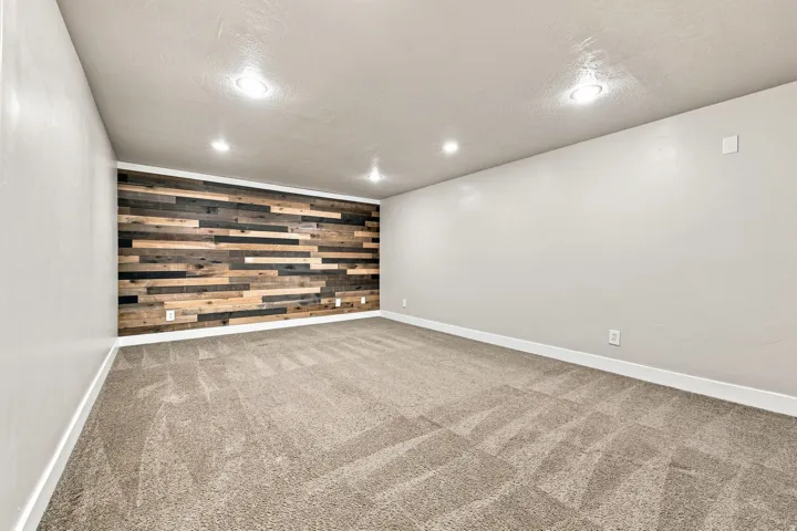 Accent wall featuring wood-finish paneling, recessed ceiling lighting, and neutral carpeting