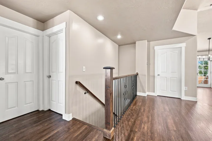 Wood-finish flooring, recessed lighting, white panel doors, and a wrought iron banister