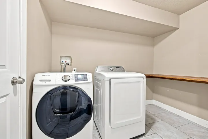 Laundry area with stone tile flooring and a wood-finish shelf